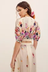 Top corto cruzado de viscosa con escote en V, mangas cortas abullonadas y diseño estampado con flores multicolores sobre fondo beige.