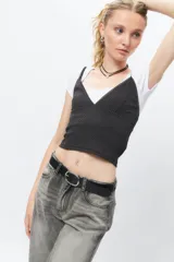 Top negro con estampado de cuadros blancos, escote en V y mangas largas.