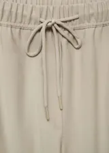 Pantalon de corte recto y diseño jogger, confeccionado en tejido fluido color beige. Presenta cintura elástica con cordón ajustable, tiro alto y bolsillos laterales.