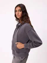 Canguro con cierre frontal y capucha, color gris con efecto desgastado. Presenta bolsillos laterales y logo bordado en el pecho.