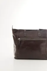 Cartera de cuero vacuno color marrón, de diseño amplio con paneles combinados de diferentes texturas y un panel central con relieve de cocodrilo. Cuenta con cierre frontal vertical y asas de hombro.