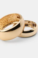 Pack de dos pulseras rígidas de metal dorado con diseño liso y acabado brillante. Cuentan con cierre magnético articulado.