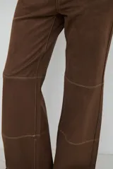 Pantalón de corte recto confeccionado en gamuza color marrón, con costuras a la vista en tono contrastante y diseño de paneles horizontales en las piernas.