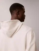 Buzo con capucha de Calvin Klein en color beige, confeccionado en mezcla de algodón y poliéster. Cuenta con bolsillo tipo canguro frontal, cordones ajustables y el monograma de la marca bordado en el pecho.