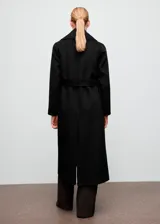 Abrigo largo de corte recto confeccionado en mezcla de lana, con cuello de solapa, manga larga y cierre frontal mediante cinturón tipo batín. Presenta abertura posterior en el bajo y forro interior.