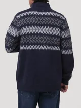 Sweater de punto con cierre frontal parcial y cuello alto. Presenta un diseño de patrón geométrico tipo jacquard en tonos grises y celestes sobre una base azul marino en la parte superior y mangas.
