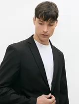 Ambo semi slim de color negro, compuesto por un saco estructurado de dos botones con solapa de muesca tradicional y un pantalón de corte contemporáneo.
