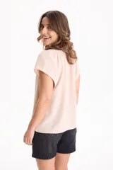 Blusa negra de manga corta, confeccionada en tela crepé, con detalle de fruncido en el escote redondo y pequeña abertura frontal en V.
