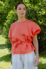 Blusa color salmón de manga tres cuartos con leve volumen, largo hasta la cadera y cinto extraíble en la espalda.