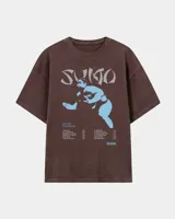 Remera marrón oversize con efecto acid wash, corte amplio y mangas cortas. Presenta un estampado frontal en tonos celestes y grises con la inscripción 'Sumo', una ilustración de un luchador de sumo y detalles tipográficos alusivos a un álbum musical.