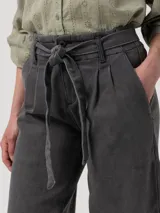 Pantalón de jean tiro alto con corte recto y pernera ancha. Presenta una pretina con lazo ajustable del mismo tejido, pinzas frontales y elástico en la parte posterior de la cintura.