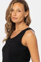 Musculosa blanca sin mangas, de corte clásico y calce cómodo, confeccionada en tejido suave. Presenta escote redondo, cartera con botones frontales y un pequeño bolsillo aplicado en el pecho.