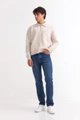 Sweater de punto color beige con cuello polo, cierre frontal parcial y bolsillo en el pecho. Presenta mangas largas con puños acanalados y diseño de corte recto.