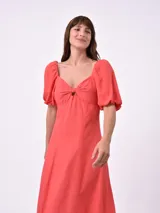 Vestido midi de color negro, con escote corazón, detalle de nudo en el centro del busto y mangas cortas abullonadas. Presenta un corte entallado en la parte superior y falda con caída fluida.