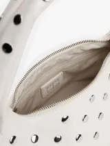 Bolso de hombro blanco con forma curva y correa corta. El cuerpo del bolso está decorado con tachuelas metálicas redondas plateadas. Posee cierre superior con cremallera.