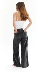 Pantalón de jean negro con costuras blancas y corte amplio.