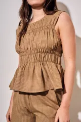 Blusa sin mangas de viscosa con estampado a cuadros vichy en tonos marrones y tostados, con doble fruncido elástico en el pecho y la cintura que genera un sutil vuelo inferior.