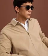 Campera de sarga color beige con cuello inglés, cierre frontal de cremallera, mangas largas y bolsillos laterales. Diseño minimalista y versátil con forro interior.