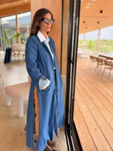 Tapado largo de jean azul, con diseño abierto sin botones, mangas largas y tajos laterales profundos. Confeccionado en denim suave y flexible.