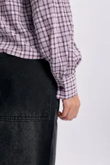 Camisa de manga larga con estampa a cuadros en tonos violeta y blanco, con cuello babero amplio con volados y cierre frontal abotonado.