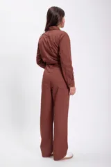 Enterito marrón de jean con cuello camisero, manga larga, cierre frontal con botones, bolsillos en el pecho y laterales.