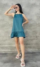 Vestido corto color verde esmeralda de satén, con breteles finos que se atan en los hombros, corte recto y volado en el ruedo.