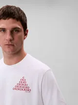 Remera blanca de manga corta y cuello redondo de la marca Calvin Klein, con calce regular. Presenta un diseño gráfico frontal en forma de pirámide formado por las letras CK en color bordó.