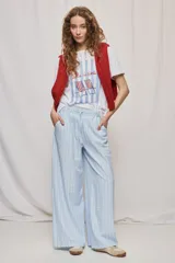 Pantalón de tiro alto con silueta amplia y caída fluida, confeccionado en tejido celeste con textura a rayas finas. Cuenta con cintura elástica con lazo de ajuste y bolsillos laterales.
