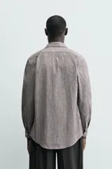 Camisa de corte regular fit confeccionada en algodón, con diseño de rayas verticales finas, cuello italiano, manga larga con puños abotonados y cierre frontal de botones.