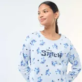 Pijama de dos piezas compuesto por una remera de manga larga y un pantalón largo, ambos en color celeste con estampado integral del personaje Stitch y pequeños corazones negros. La remera presenta el nombre del personaje en el frente.