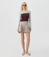 Short pollera de tiro alto en color beige, con diseño de sastrería, tablas delanteras y ruedo asimétrico.
