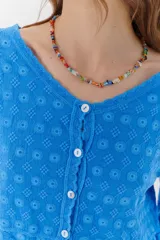 Camisa color crema con bordados florales, escote en V, mangas largas y cierre frontal con botones.