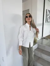 Camisa negra con cuello alto, mangas largas abullonadas y cierre frontal con botones. Presenta detalles de encaje y lentejuelas en el frente.