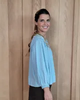 Camisa de manga larga con diseño de rayas verticales y bordados sutiles. Presenta cuello redondo, cierre frontal con botones y mangas abullonadas con volados en los hombros.