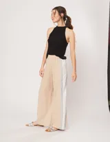 Pantalón palazzo color beige con cintura elastizada y dos franjas verticales en los laterales, una plateada y otra blanca.