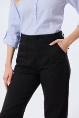 Pantalón de gabardina marrón, de corte recto con pinza en el bajo y detalles de botones en los tobillos.