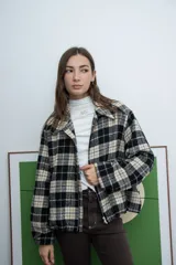 Chaqueta de corte recto con cierre frontal, cuello camisero y diseño a cuadros en tonos negro y beige.