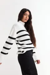 Sweater de punto con cuello alto, diseño de rayas horizontales en color blanco y negro, mangas largas y corte holgado.
