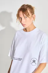 Remerón blanco de jersey 24/1 peinado, corte oversized, mangas cortas y ruedo ancho. Estampa serigrafiada en frente y espalda a contratono.