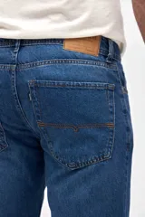 Jean de corte recto y tiro medio, confeccionado en denim de color azul clásico con costuras reforzadas y cierre frontal con botón.