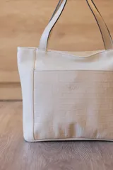 Cartera tipo tote de cuero vacuno negro con doble asa de hombro, panel superior liso y bolsillo exterior frontal con textura símil cocodrilo y costuras visibles en contraste.