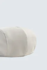 Boina de estilo clásico con visera corta, confeccionada en tejido de lana color marrón oscuro.