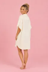 Vestido camisero corto color beige, confeccionado en viscosa suave y liviana, con mangas cortas, cuello camisero y diseño holgado.