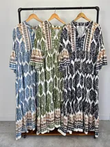 Maxi vestido largo de fibrana en color blanco con estampado paisley y geométrico en tonos azules y tostados, con escote en V, mangas largas amplias y diseño holgado con volados en la falda.