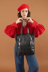Bolso tipo tote negro de cuero vacuno con textura croco en los laterales y cierres plateados.