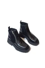 Botas cortas negras con plataforma dentada, confeccionadas en una combinación de cuero con textura de reptil y paneles de gamuza. Presentan un cierre frontal metálico y puntera cuadrada.