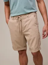 Bermuda color beige de algodón y lino, con cordón ajustable en la cintura y ruedo doblado.
