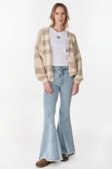 Cardigan tejido de punto a rayas horizontales en tonos crudo y beige, de manga larga y diseño holgado.
