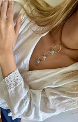 Gargantilla corta con cadena de cuero marrón y eslabones ovalados dorados unidos por piedras rectangulares facetadas de color celeste.