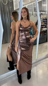 Vestido largo de fiesta en tono chocolate metalizado, con escote halter y diseño drapeado en el frente. Presenta un tajo lateral pronunciado y espalda descubierta.